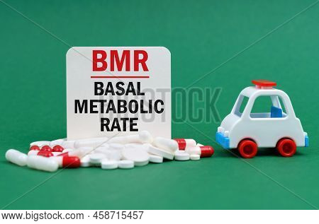 On A Green Surface, An Ambulance, Pills And A White Sign With The Inscription - Basal Metabolic Rate