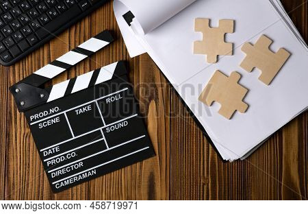 Black Movie Clapper With Keyboard And Script Sheets With Puzzle On A Wooden Table