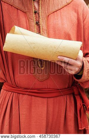 A Man In Vintage Medieval Clothes With A Paper Letter In His Hand. Reconstruction Of The Events Of T