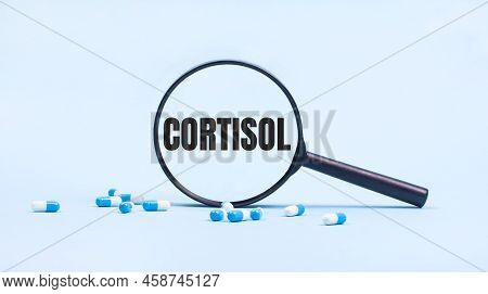 On A Blue Background, White And Blue Capsules With Pills And A Black Magnifying Glass With The Text 