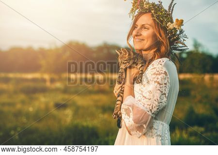 Woman In Flower Wreath On Sunny Meadow With Cat.