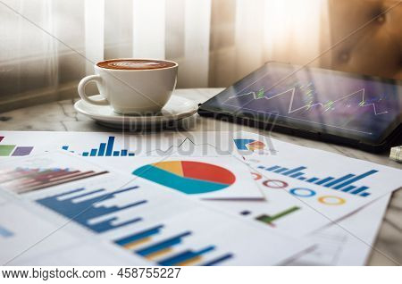 Close Up View, Latte Coffee In White Cup With Chart Of Investment And Tablet Computer On Table In Ca