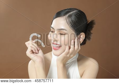 A Young Woman With Beautiful Teeth Is Holding Invisalign, Healthy Dental Concept