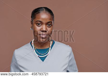Portrait Of African Female Social Worker In Blue Uniform Standing Against Beige Background