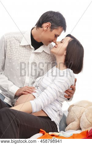 Happy Caucasian Family With Pregnant Whife And Caring Husband While Kissing And Embracing His Woman