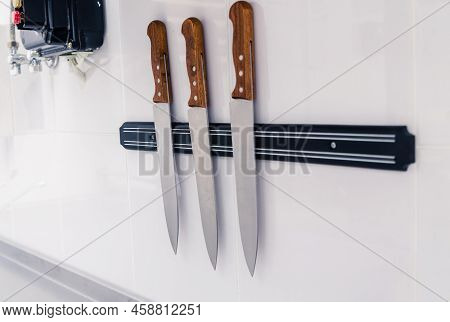 Set Of Knives On Magnetic Holder On White Wall. Horizontal Photo