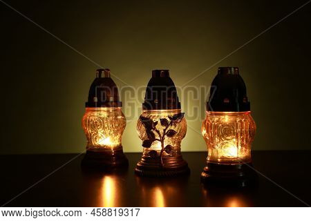 Beautiful Glowing Grave Lights On Table In Darkness. Symbol Of Remembrance