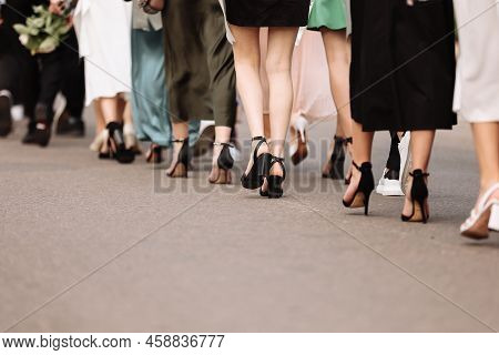 The Feet Of The Group Of People Are Walking Outdoors. Graduation Day. Stylish Young Guys And Girls I