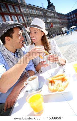 Cheerful couple of tourists eating churros in Madrid