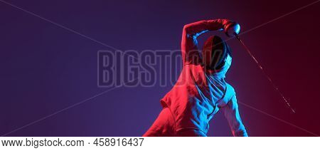 Male Fencer With Smallsword Practicing Fencing Isolated On Purple Background In Neon Light. Sport, E