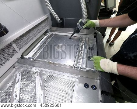 A Male Worker Cleans The Surface Of An Industrial 3d Printer From White Powder With A Vacuum Cleaner