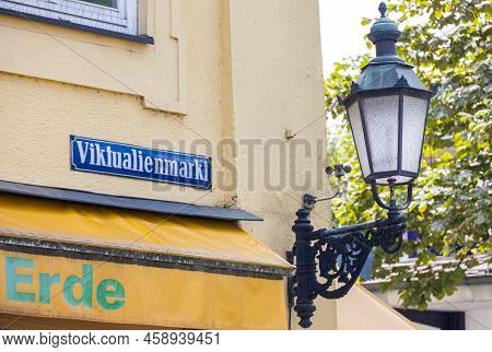 Munich, Germany - July 6, 2022: Street Sign Of The Viktualienmarkt With A Historic Street Lamp Besid