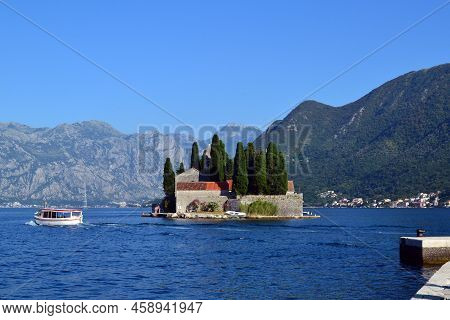Montenegro. The Photo Shows A View Of The Island With Buildings And Trees. In The Background Is A Ph