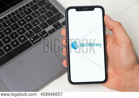 Webmoney Financial Platform For Money Transfer Using Smartphone. Man Hand Holding A Mobile Phone Wit