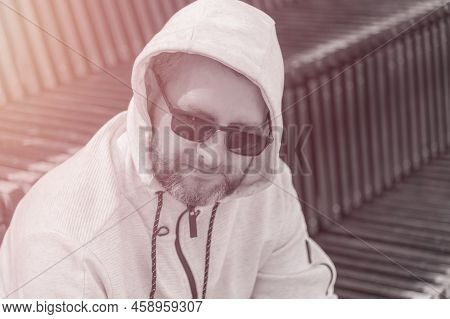 Portrait Of A Senior Man With Grey Hair And Sunglases Wearing A Hooded Sweater