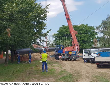 Laying Heating Pipes In A Trench At Construction Site. Reconstruction Site Of District Heating Syste
