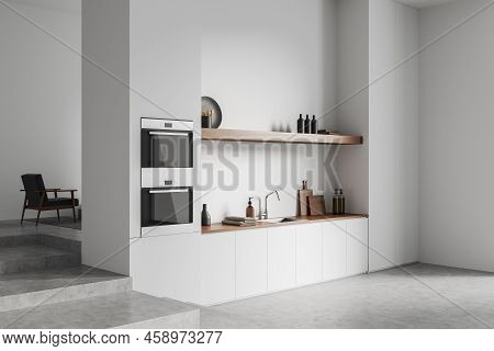 Corner View On Bright Kitchen Room Interior With Cupboard, White Wall, Concrete Floor, Oven, Shelves