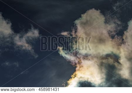 Diffraction Of Light On Drops Of Supercooled Water In Clouds, Rainbow Clouds Against The Blue Sky In