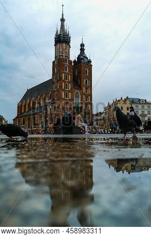 Cracow, Poland - July 3 2021: Facade Of St. Mary's Church Reflected In Puddle