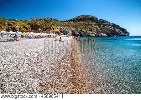 Traganou, Greece - July 1, 2022: Vacationers Relaxing At Pebble Traganou Beach At Rhodes Island In G