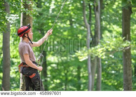 Man Belays His Partner Climber With Belaying Device And Rope. Climbers Handsman Holding Equipment Fo