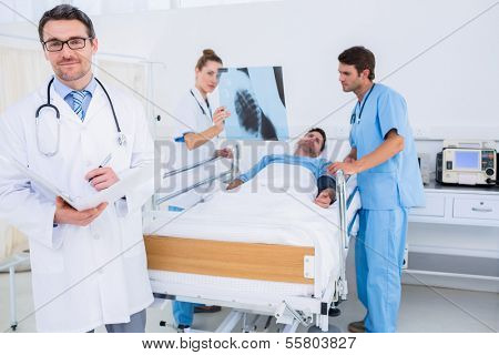 Doctors holding reports by patient in bed at the hospital