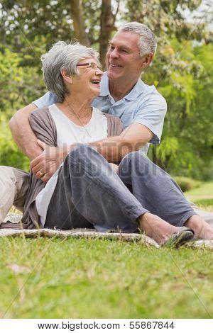 Happy senior man embracing woman from behind at the park