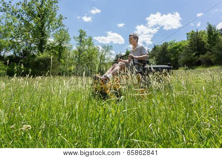 Senior Man On Zero Turn Lawnmower In Meadow