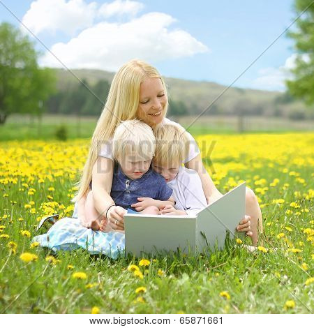 Mother Reading Book To Young Children Outside