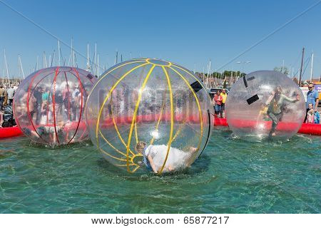 Children Have Fun Inside Plastic Balloons On The Water During A Fishing Fare