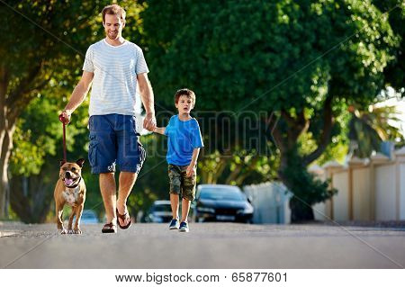 A father walking with his dog and his son in the suburbs