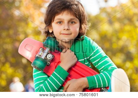 Happy boy in green sweater with red skateboard