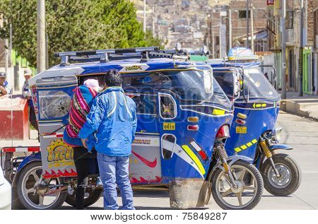 PUNO, PERU, MAY 5, 2014: Local couple enters an auto rickshaw waiting on street