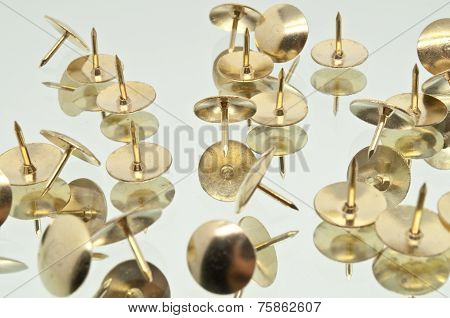 A Collection of Thumbtacks On A Mirror