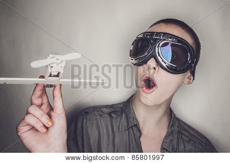 girl in retro pilot glasses with wooden plane
