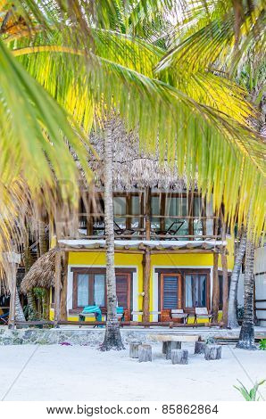 Tropical Villa View Through Palm Trees At Exotic Sandy Beach