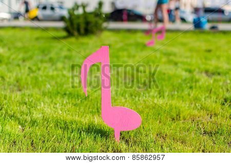 The Sketch Of Musical Pink Notes Over The Green Lawn
