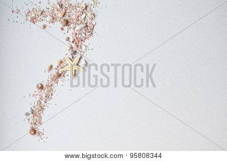 Sea shells, pink sand and a starfish on a paper background