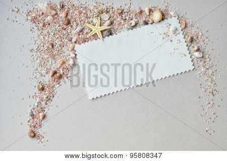 Sea shells, pink sand and invitation card on a paper background