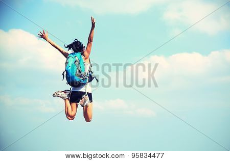 young asian woman jumping against blue sky