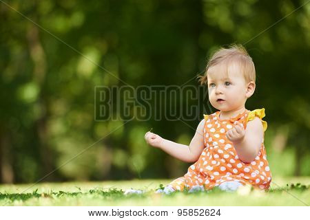 happy young baby child sittng on grass on beautiful summer day in park