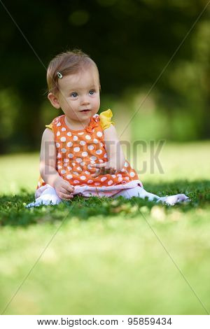 happy young baby child sittng on grass on beautiful summer day in park