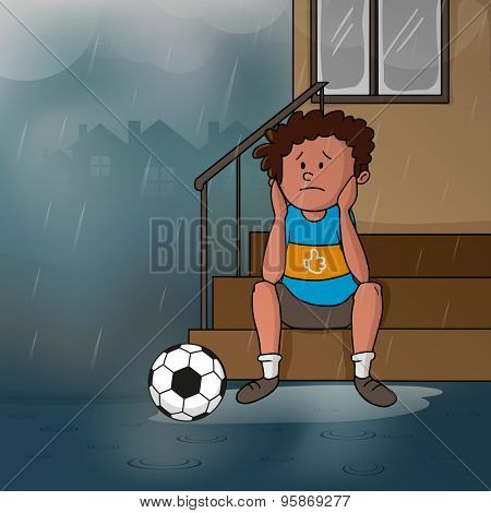 Cute little sad boy sitting at stairs with soccer ball in a rainy day for Mossoon Season concept. 