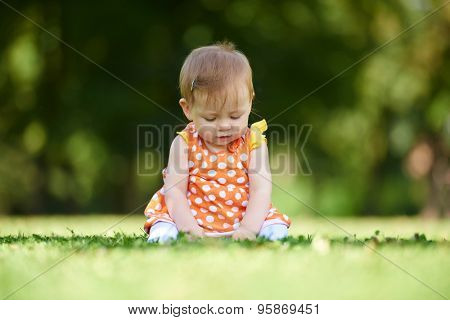 happy young baby child sittng on grass on beautiful summer day in park