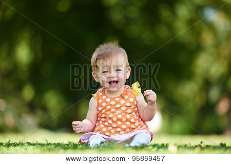 happy young baby child sittng on grass on beautiful summer day in park