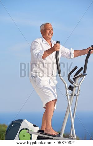 healthy senior man working out on gym treadmill machine at modern home terace with ocean view