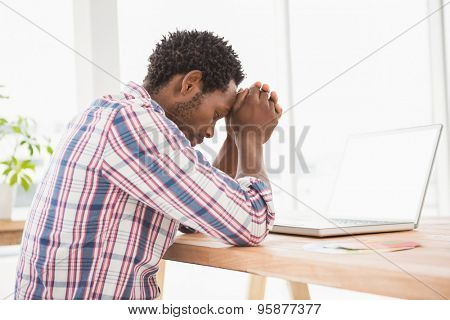 Young businessman being uneasy at his desk in front of the laptop in his office