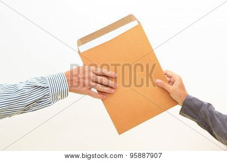 Woman's Hand Passes Envelope To Male Hand On White Background