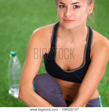 Beautiful young woman relaxing after exerscises on the grass