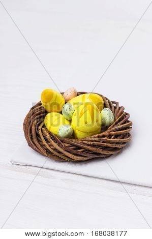 Easter eggs in nest on white wooden background